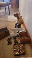 Photo showing boxes on floor with some wood carved elephant figurines and a box full of brass miniatures.