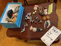 Overall view of box and laid out clip-on earrings showing variety of pairs