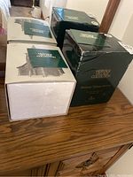 Photo of two boxed vintage Heritage Village Collection buildings from the Dickens Village Series, showing packaging condition and accessories including booklets.