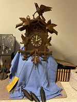 Front view of cuckoo clock on blue cloth with two weights visible