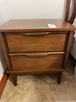 Front view of the walnut side table showing two drawers with curved wooden handles and tapered legs.