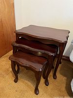 Set of three wooden nesting tables stacked inside each other, showing size difference and leg design.