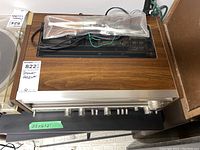 Receiver top and front angle showing wood grain enclosure, control panel, and included cables in plastic bag.