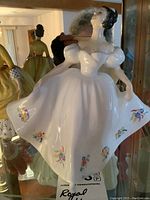 Front view of Royal Doulton Kate HN 2789 figurine showing white dress with floral patterns and puffed sleeves.