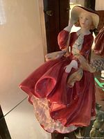 Front side view of Royal Doulton porcelain figurine in red dress and hat