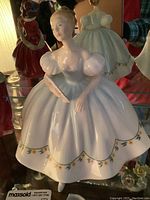 Front angle of the Royal Doulton porcelain figurine showing blue and white gown with floral accents and fan in hand.