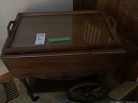 Wood tea cart with removable glass and wood tray top, showing front and side with large wooden wheel and small caster.