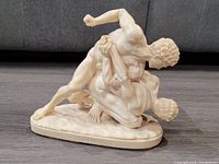 Side view of Santini wrestling scene sculpture, showing muscular figures locked in combat.