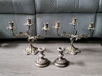 Full view of two large candelabras and two small candlesticks displayed on floor
