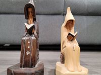 Front view of dark stained and light natural wood carved wizards or monks seated with books