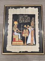 Full view of the framed papyrus painting showing the Egyptian scene with seated and standing figures and hieroglyphs.