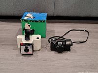 Both cameras together on the floor with The Swinger box in background