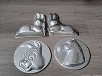 Two 3D bunny pans side by side with a round bunny face pan and a horse head pan laid on a floor.