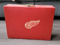Front view of the red Detroit Red Wings carrying case with logo and cream-colored handle.