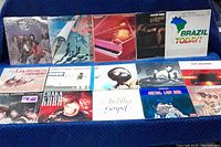 Fourteen vinyl album covers arranged on blue backdrop, first of five group shots
