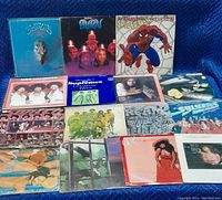 16 vinyl LPs arranged in grid on blue blanket, front covers visible