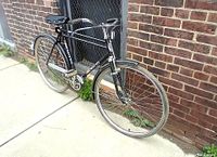 Front-side view showing double top tube frame, front wheel, mechanical brake, and part of the drivetrain.