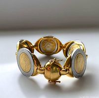 Close-up showing the detailed coin motifs on the bracelet links and the clasp mechanism.