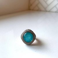 Front view showing round turquoise-colored center stone and clear topaz halo on 18k rose gold plated Milor bronze ring