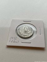 Reverse side of 1952 silver US quarter coin showing eagle design, in protective holder marked with '1952 (silver)' handwritten.