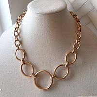 Full view of the Italian-crafted Milor bronze necklace displayed on a beige fabric bust, showing large and medium oval links and the polished 18k rose gold plating finish.