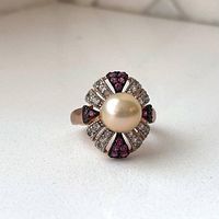 Front view displaying the central blush pearl with fan-like arrangement of clear and amethyst stones on rose gold plated band.