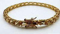 Front angle of the gold plated sterling silver tennis bracelet showing oval-cut yellow-toned gemstones and clasp.