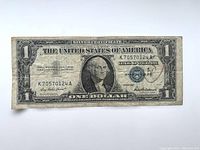 Front side of the worn 1957 Series US one dollar bill with visible wear and the serial number K70570124A.