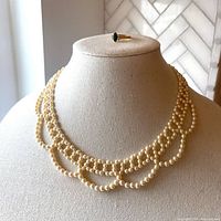 Front view of multi-strand faux pearl necklace displayed on mannequin bust showing the elegant layered design and ivory color.