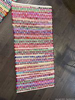 Single folded rug showing vibrant woven geometric pattern in multiple colors on poly-cotton fabric.