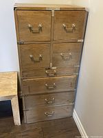 Front view of the tall campaign chest showing six drawers, metal corner brackets, and handles.