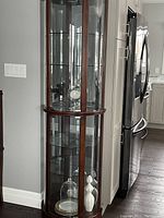 Front view of half-round curio cabinet next to refrigerator