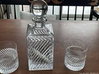 Front view of cut crystal decanter with stopper flanked by two matching scotch glasses.