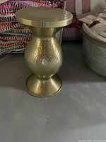Full view of hourglass-shaped hammered brass table showing overall form and finish