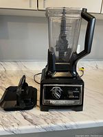Ninja Ultima Blender with black base and clear glass jar with handle and black lid placed next to it on a countertop.