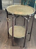 Two-tier Moroccan side tray table showing both brass trays and dark wooden folding legs