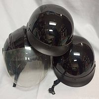 Three black motorcycle helmets grouped together including one with clear face visor.
