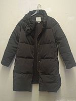 Full front view of black Kate Spade puffer coat with bow detail.
