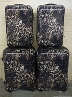 Four hardshell suitcases with leopard print stacked, showing entire lot.