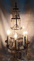 Full view of the chandelier turned on and illuminated to show working bulbs and overall shape.