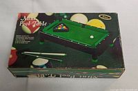 Box for mini pool table game displaying brand and game details.