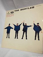 Front cover of The Beatles Help! mono vinyl album showing the four band members in stylized pose on a white background.