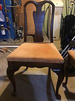 Close-up of one upholstered chair showing carved wooden backrest and peach/beige cushioned seat.