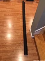 Full length view of the roll of black screen material laid out on wood floor, showing approximate length and end of roll.