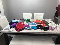 Overview of all women's swimsuits laid flat on a white table, showing a variety of colors and styles including one-pieces and two-piece sets.