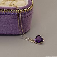 14kt gold chain draped over velvet box with heart-shaped amethyst pendant attached