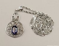 Coiled 20" chain with attached filigree pendant set with oval iolite on white background