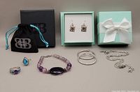 Photo showing full set of jewelry including necklace, rings, earrings, bracelet and original boxes/pouch.