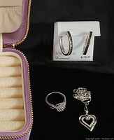 Sterling silver necklace with heart-shaped pendant, ring with small diamonds, hoop earrings with black diamonds, and new velvet jewelry box shown inside box.
