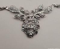 Close-up front view of vintage sterling silver necklace pendant shaped as a rose with marcasite stones set in detailed leaves and petals.